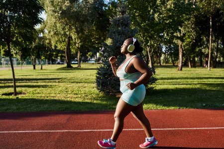 An African American woman in sportswear, celebrating her curves, runs gracefully on a tennis court in an outdoor setting.