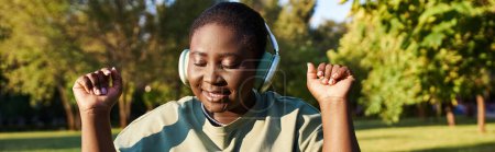 Une jeune femme passionnée de musique, portant des écouteurs, profitant du cadre serein d'un parc.