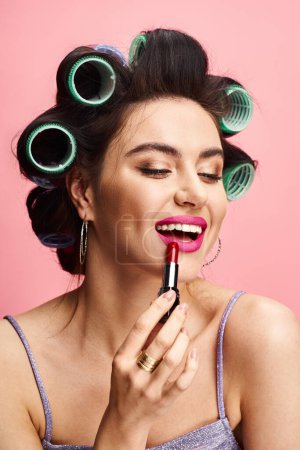 Stylish woman with curlers in her hair holding a lipstick, against a vibrant backdrop.