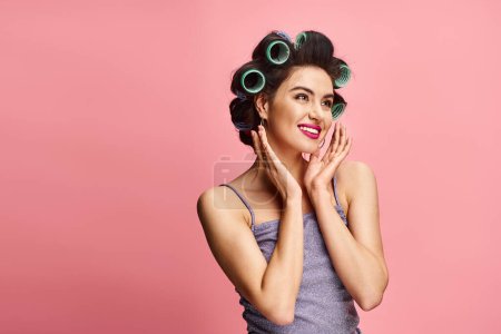 Téléchargez les photos : A vibrant backdrop frames an attractive woman with curlers in her hair posing confidently. - en image libre de droit