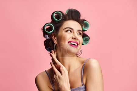 Woman with curlers in her hair posing elegantly for the camera on a colorful backdrop.