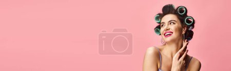 Téléchargez les photos : Femme élégante avec des bigoudis dans les cheveux sur fond rose vif. - en image libre de droit