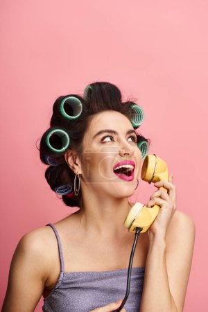 Photo for A stylish woman with curlers in her hair talking on a retro phone. - Royalty Free Image