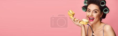 Photo for Stylish woman with curlers in her hair poses playfully with a retro phone. - Royalty Free Image