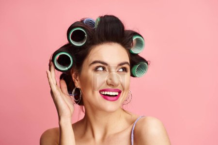 Photo for A stylish woman with curlers in her hair striking a glamorous pose. - Royalty Free Image