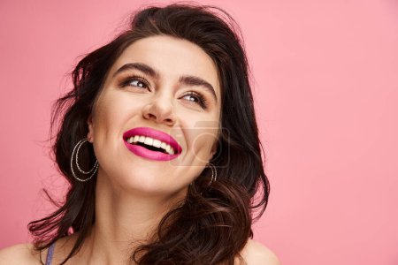 A striking woman with long dark hair and pink lipstick poses gracefully against a vibrant backdrop.