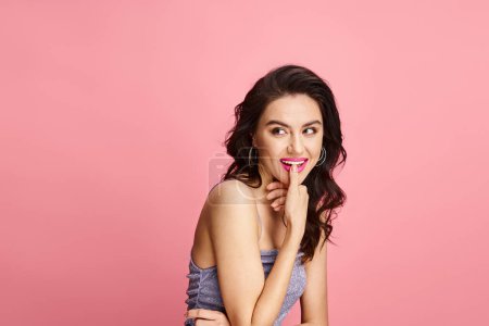 Woman posing actively on pink backdrop.
