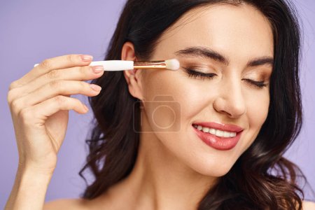 Photo for A woman delicately applies eyeshadow with a makeup brush. - Royalty Free Image