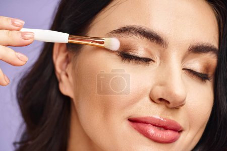 Téléchargez les photos : Beautiful woman enhancing natural beauty with a brush in her eye. - en image libre de droit