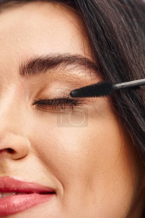 A woman perfecting with a mascara, emphasizing natural beauty.