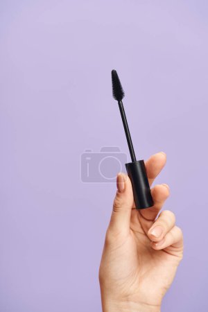 Eine Frau unterstreicht ihre natürliche Schönheit mit schwarzer Mascara in der Hand.