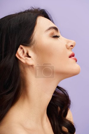 Photo for A woman with long black hair gracefully applies makeup against a soft pink background. - Royalty Free Image