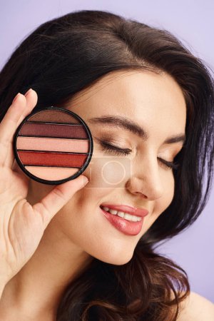 A woman with natural beauty holds a palette and applies makeup.