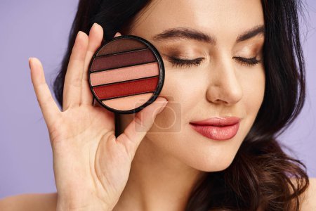 Appealing woman with natural beauty holds a palette and applies makeup.