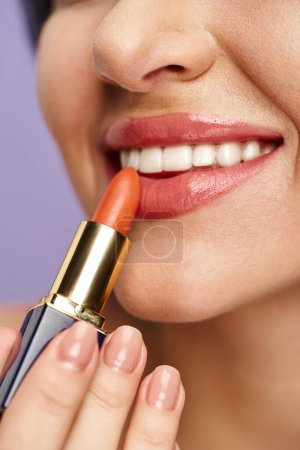 Photo for A woman applying lipstick with precision. - Royalty Free Image