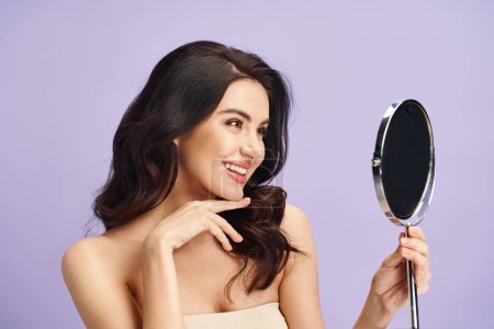 Photo for Woman in strapless dress gazes at herself in mirror while applying makeup. - Royalty Free Image