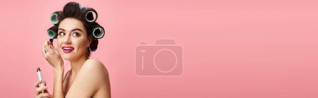 Téléchargez les photos : Une femme élégante avec des bigoudis dans ses cheveux tenant maskara. - en image libre de droit
