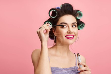 Stylish woman with curlers in hair applying makeup.