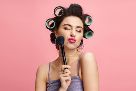 Photo for A woman with curlers in her hair holds a brush. - Royalty Free Image