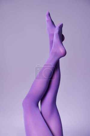 Foto de A young womans legs clad in striking purple stockings and a matching backdrop in a studio. - Imagen libre de derechos