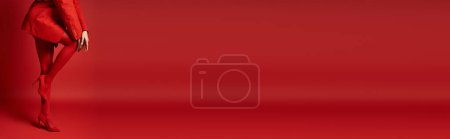 Téléchargez les photos : Une jeune femme vêtue d'une veste rouge vibrante se dresse hardiment sur un fond assorti dans un décor de studio. - en image libre de droit