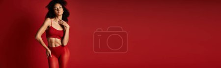 Photo for A young woman in red lingerie strikes a pose for a photograph against a vibrant background in a studio setting. - Royalty Free Image