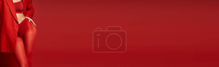 Téléchargez les photos : Une jeune femme dans un collant rouge frappant sur fond de studio vibrant. - en image libre de droit