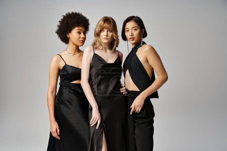 Eine Gruppe schöner Frauen unterschiedlichster Herkunft steht in eleganter Frühlingskleidung vor grauem Studiohintergrund zusammen..