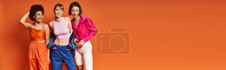 Photo for Diverse group of women, including Caucasian, Asian, and African American, standing side by side against an orange background. - Royalty Free Image