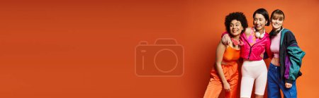 Téléchargez les photos : Un groupe de femmes, représentant diverses cultures, se tiennent côte à côte dans un studio orange. - en image libre de droit