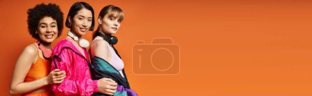 Téléchargez les photos : Un groupe de femmes de différentes ethnies et cultures se tenant l'une à côté de l'autre devant un fond orange. - en image libre de droit