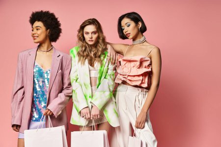 Eine Gruppe schöner Frauen mit Einkaufstaschen, die die Vielfalt mit kaukasischen, asiatischen und afroamerikanischen Damen auf rosa Hintergrund präsentieren.