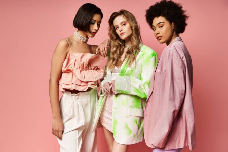 Eine bunte Gruppe von drei zusammenstehenden Frauen, die für Multikulturalismus und Schönheit stehen, vor rosa Studiohintergrund.