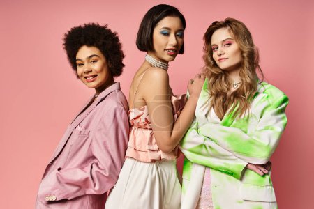 Drei Frauen unterschiedlicher ethnischer Zugehörigkeit stehen gemeinsam auf einem rosafarbenen Hintergrund und zeigen Vielfalt und Einheit.