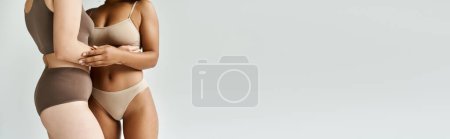 Photo for Two beautiful diverse women stand next to each other in cozy pastel underwear. - Royalty Free Image