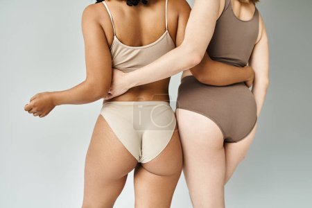 Foto de Dos hermosas mujeres diversas en acogedora ropa interior pastel de pie lado a lado. - Imagen libre de derechos