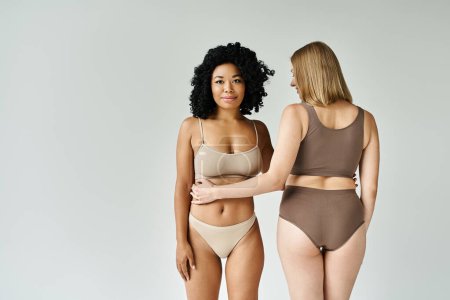 Photo for Two beautiful diverse women standing in cozy pastel underwear. - Royalty Free Image
