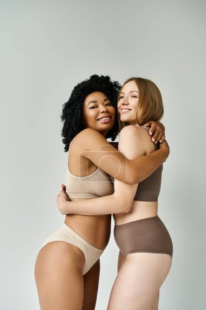 Foto de Dos hermosas mujeres en acogedora ropa interior de pastel abrazándose calurosamente. - Imagen libre de derechos