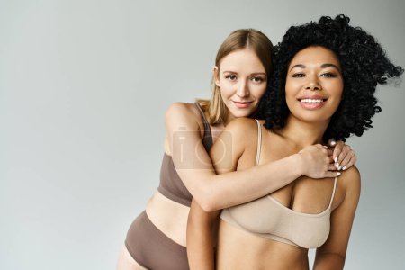 Téléchargez les photos : Deux belles femmes diversifiées dans des bikinis pastel douillettes s'embrassant amoureusement. - en image libre de droit