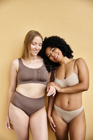 Dos mujeres diversas posan elegantemente en ropa interior pastel acogedor.