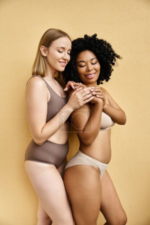 Foto de Dos hermosas mujeres diversas en ropa interior de pastel acogedor posando para una imagen. - Imagen libre de derechos