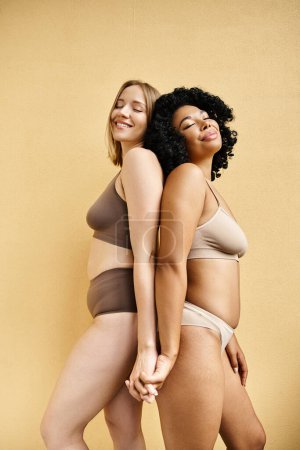 Foto de Dos hermosas mujeres de pie con confianza en acogedores bikinis pastel. - Imagen libre de derechos