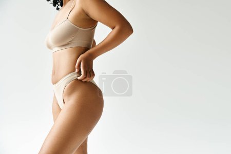 Eine schöne, vielseitige Frau in einem gebräunten Bikini posiert für die Kamera.