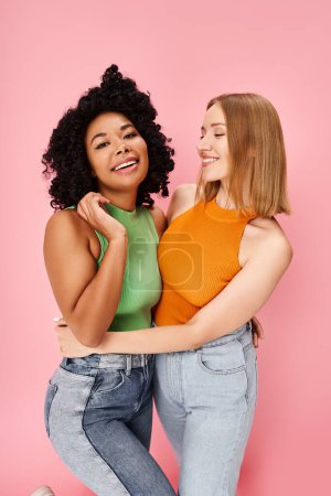 Photo for Two women, diverse and stylish, share a warm hug against a soft pink backdrop. - Royalty Free Image