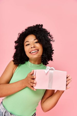 Woman in green shirt holding a pink gift box.