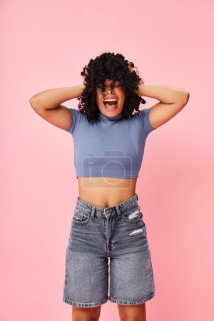 Photo for A woman exudes confidence in a blue crop top and denim shorts. - Royalty Free Image