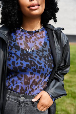 Eine Frau mit verschiedenen ethnischen Zugehörigkeiten trägt ein blaues Oberteil und eine schwarze Jacke.