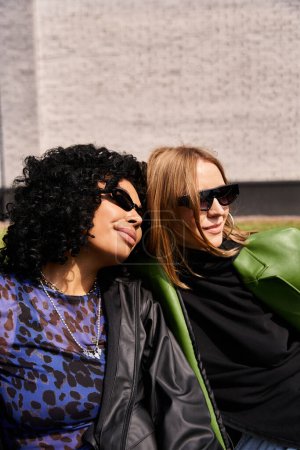 Foto de Dos mujeres diversas, vestidas casualmente, sentadas de cerca con un comportamiento cálido y amistoso. - Imagen libre de derechos