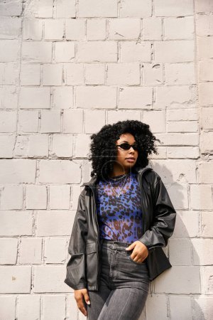 Foto de Una mujer con estilo en ropa casual se encuentra junto a una pared de ladrillo texturizado. - Imagen libre de derechos