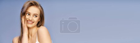 Une jeune femme blonde respire la grâce dans un bikini blanc alors qu'elle pose pour la caméra dans un décor de studio.